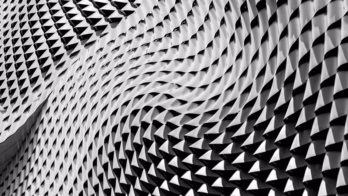 Black and white building facade of pointed studs arranged in a swirling wave pattern