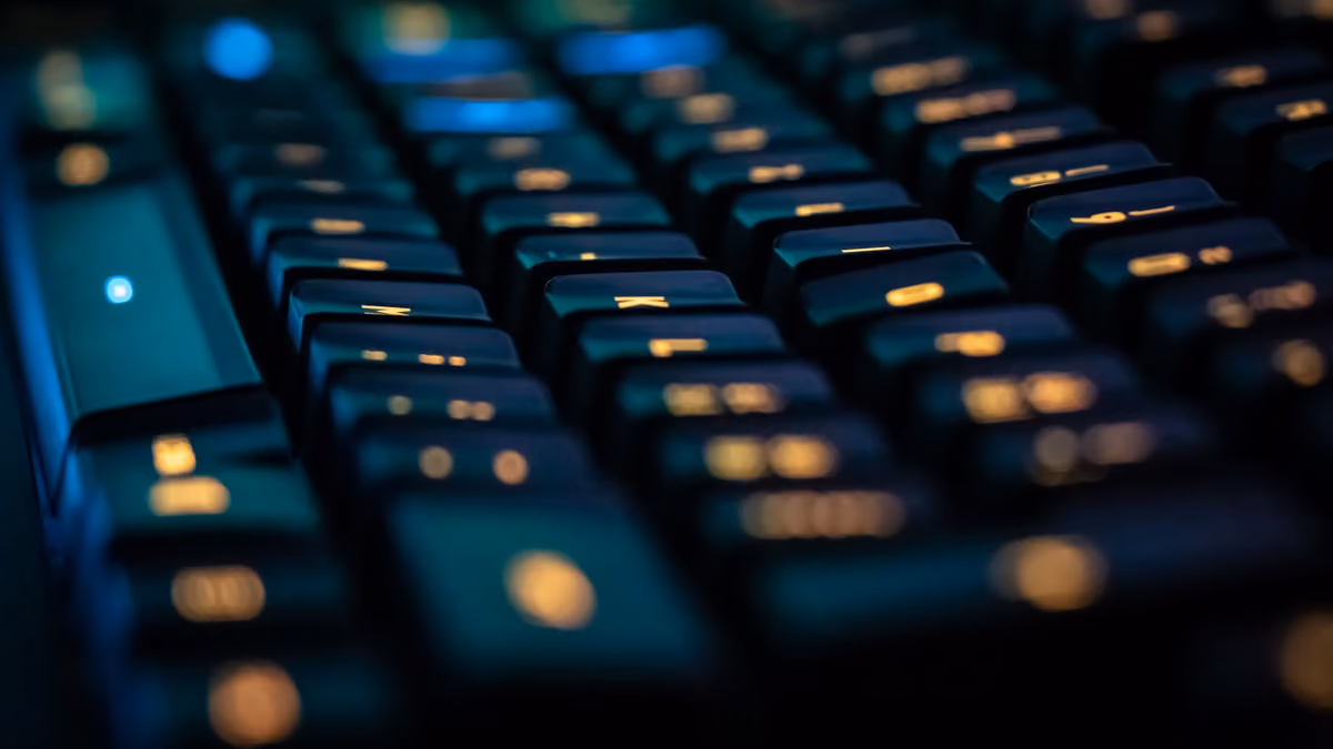Extreme close-up of a backlit mechanical keyboard with keys glowing teal and amber